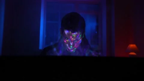 Man Uses a Laptop that Illuminates Him with Multi-Colored Neon Light Stock Footage 232407582
