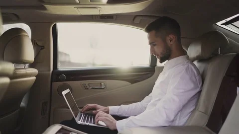 Man uses laptop sitting in back seat of car, businessman in taxi Stock Footage 81596823