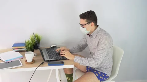 Man uses laptop, typing text. Young guy works remote at home on gray background. Stock Footage 131474450