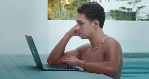 Man uses a laptop while relaxing in pool. Businessman remotely works on a laptop Stock Footage 249615951