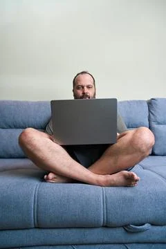 Man uses laptop while sitting on sofa Stock Photos