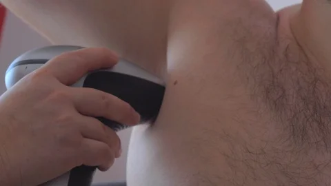 A man uses a laser epilator for epilation at home. Photoepilation of armpit. Stock Footage 112881997