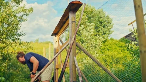 A Man Uses a Level Tool to Align a Wooden Fence Post in a Grassy Yard - Close Up Stock Footage 330985151