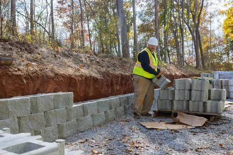 A man uses a leveling tool during the construction of a concrete block wall to Foto stock