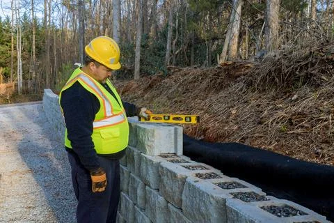 A man uses a leveling tool during the construction of a concrete block wall to Foto stock