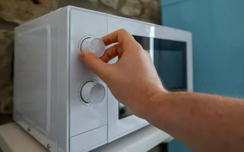 Man uses a microwave oven in the kitchen. Stock Photos