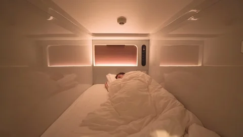 A man uses a mobile device while in a capsule hotel, Japan. Self quarantine. Stock Footage 126917762