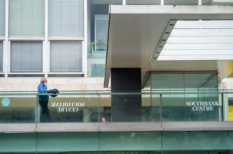 Man uses mobile phone while leaning on railings outside the South Bank Centre Stock Photos