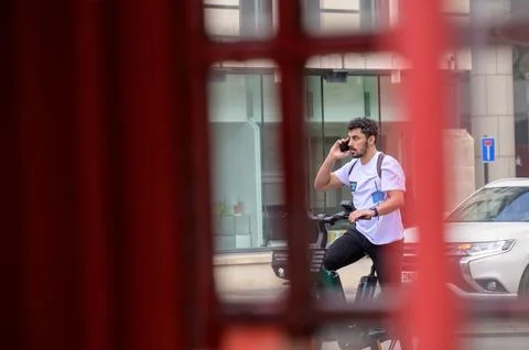 Man uses mobile phone while on rental electric bike Stock Photos