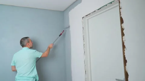 A man uses a paint roller to paint the wall gray. Stock Footage 166547663