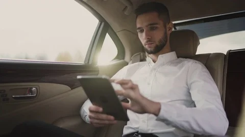 Man uses pc tablet sitting in back seat of car, businessman in taxi Stock Footage 81596538