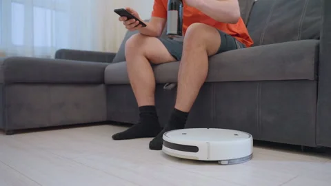 Man Uses Phone While Robot Vacuum Delivers Bottle of Drink Stock-Footage 320021699