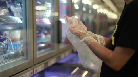 Man uses plastic bags as protective gloves at the supermarket due to COVID-19. Stock Footage 133369031