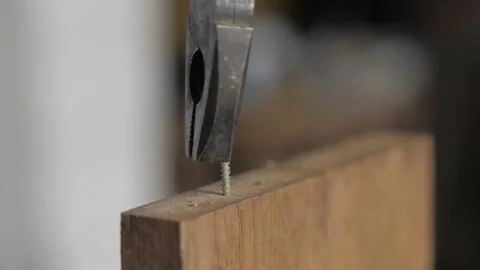 A man uses pliers to remove a screw from a piece of wood. work with a tools Stock Footage 155860966