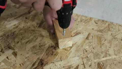 A man uses a power drill to screw a screw into a wooden board on a table. Repair Stock Footage 321390202