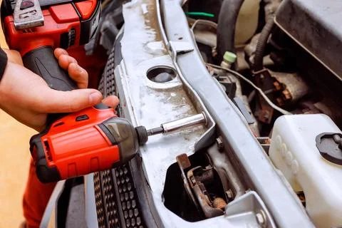 Man uses power tool to work on car engine in garage Stock Photos