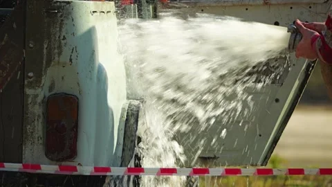 A man uses a powerful, high-pressure water jet to clean a dirty off-road vehicle Stock Footage 344875914