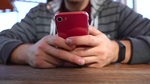 Man uses a red phone while sitting at a table Stock Footage 139131121