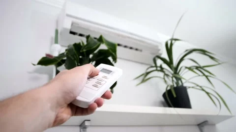 Man uses a remote control to adjust the temperature Stock Footage 145480790