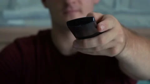 Man uses the remote while sitting in front of the TV Stock Footage 158815448