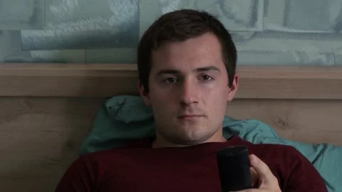 A man uses the remote while sitting in front of the TV Stock Footage 158836207