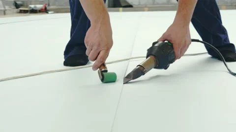 Man uses roller and tool to process white coating for pool Stock Footage 229842479