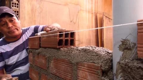 The man uses rope to maintain a straight line of bricks. Video stock 153449449