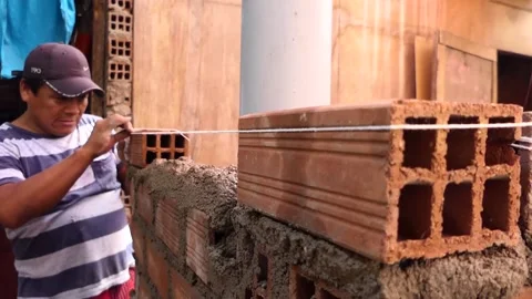 The man uses rope to maintain a straight line of bricks. Video stock 153449458