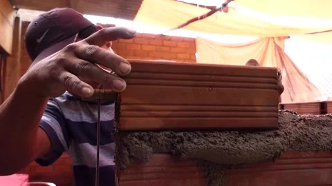 The man uses rope to maintain a straight line of bricks. Stock Footage 153449806
