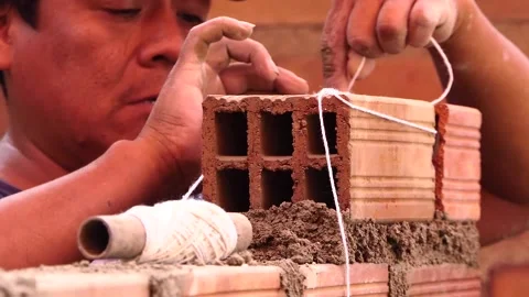 The man uses rope to maintain a straight line of bricks. Stock Footage 153450208