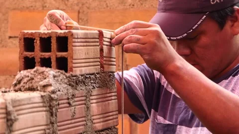 The man uses rope to maintain a straight line of bricks. Stock Footage 153451468