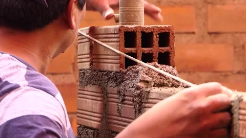 The man uses rope to maintain a straight line of bricks. Stock Footage 153451641