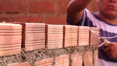 The man uses rope to maintain a straight line of bricks. Video stock 153452114