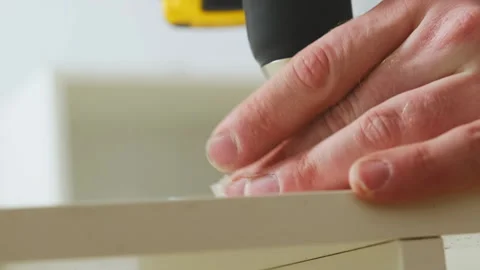 Man uses screwdriver to twist screw into boards of shelf carcass Video stock 304401066