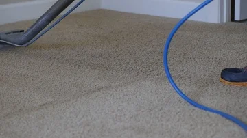 Man uses silver steam cleaner to clean the tan carpet Stockbeeldmateriaal 85870811