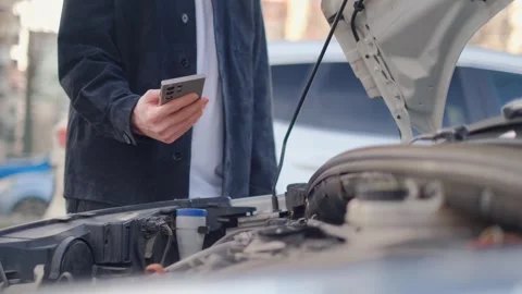 A man uses a smartphone against the backdrop of a broken-down car Stock-Footage 304007267