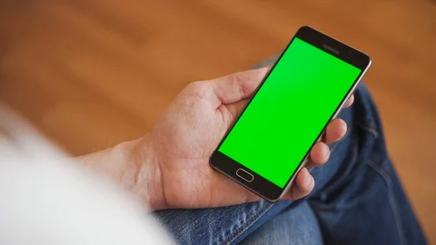 A man uses a smartphone with a green screen. 4K chroma key Stock Footage 128000090