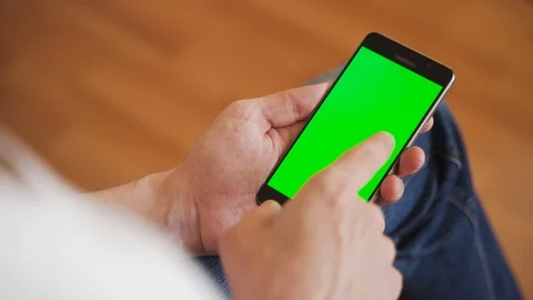 A man uses a smartphone with a green screen. 4K chroma key Stock Footage 128000099