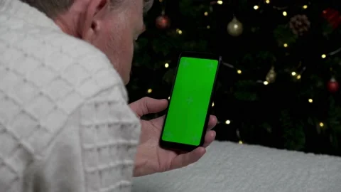 A man uses a smartphone with a green screen on the background of Christmas tree. Stock Footage 165786006