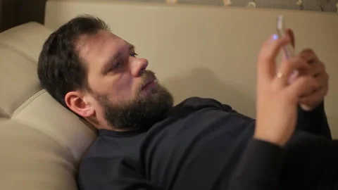 Man uses a smartphone at home on the couch in the evening Stock Footage 87312489