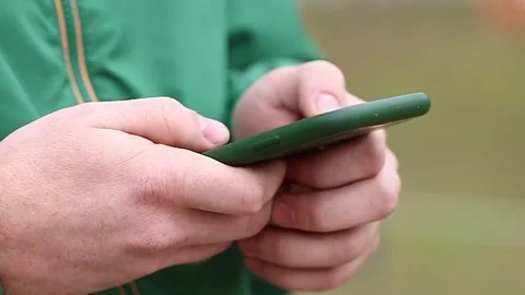 A man uses a smartphone surf the Internet on the street. Stock Footage 164566398