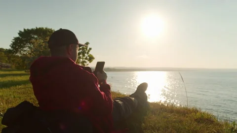 Man uses a smartphone while sitting on the seashore while traveling. Stock Footage 197745135