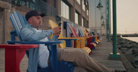 Man uses a smartphone while sitting on a bench in the city. Stock Footage 244398750
