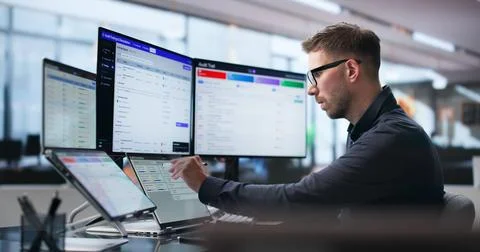 Man Uses Software Dashboard On Laptop To Track Compliance And Risks. Stock Photos