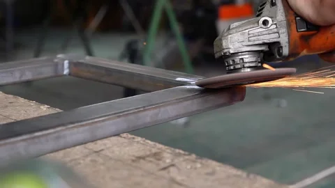 A man uses a special tool to grind metal in a workshop. Interior of a heavy mach Stock Footage 295490936