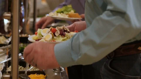 Man uses spoon to pour cheese over salad while walking through salad bar Stock Footage 89203855