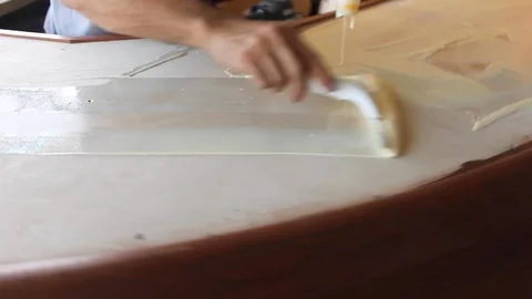 Man uses squeegee to brush to paste adhesive glue paint across a bar top B Stock Footage 125057283