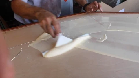 Man uses squeegee to brush to paste adhesive glue paint across a bar top C Stock Footage 125057291