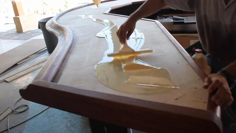 Man uses squeegee to brush to paste adhesive glue paint across a bar top A Stock Footage 125057333