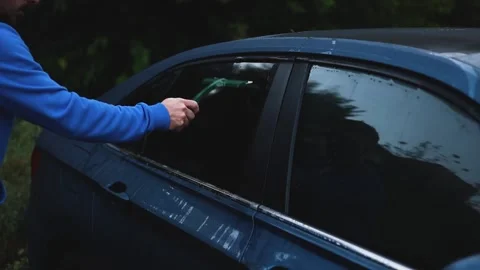 A man uses a squeegee to remove water from a car. Vidéo 317459266